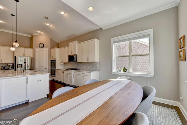 kitchen with white cabinets, appliances with stainless steel finishes, and hanging light fixtures