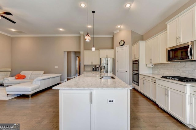 kitchen with white cabinets, stainless steel appliances, an island with sink, and decorative light fixtures