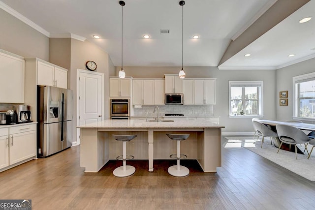 kitchen with stainless steel appliances, decorative backsplash, a center island with sink, and pendant lighting