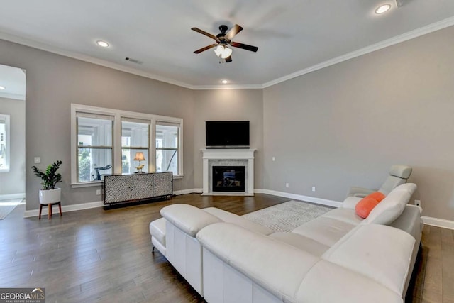 living room featuring ceiling fan, crown molding, a high end fireplace, and dark hardwood / wood-style floors