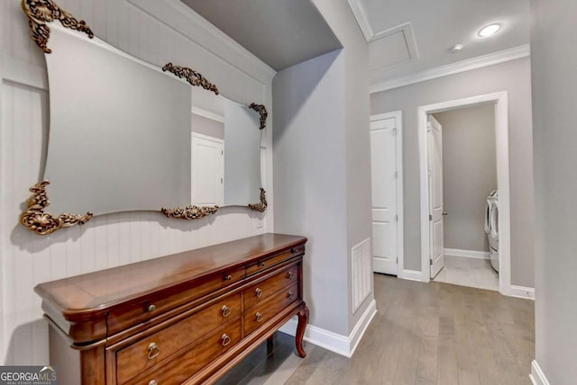 interior space with washing machine and dryer, hardwood / wood-style floors, and crown molding