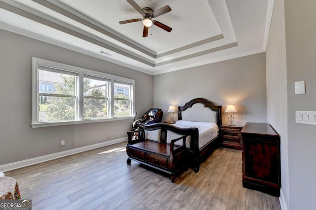 bedroom featuring ornamental molding, a raised ceiling, ceiling fan, and light hardwood / wood-style flooring