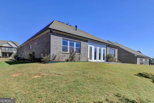 back of property featuring central air condition unit and a lawn