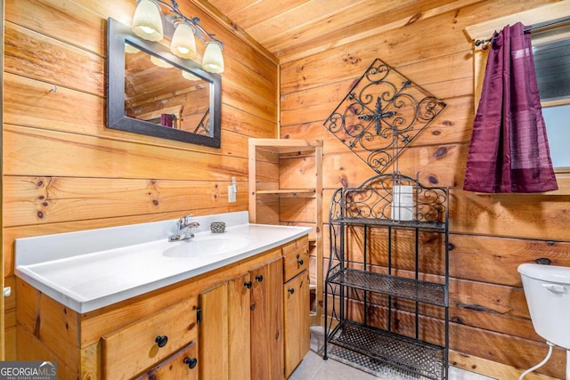 bathroom with vanity, wooden walls, and toilet