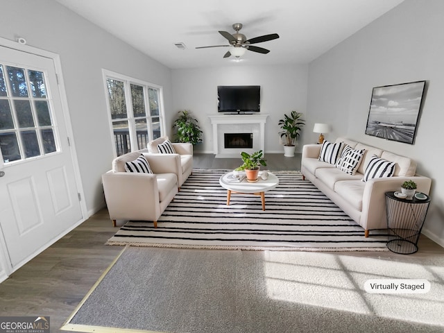 living room featuring dark wood-type flooring, a high end fireplace, and ceiling fan