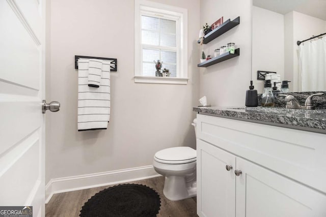 bathroom with toilet, vanity, and hardwood / wood-style floors