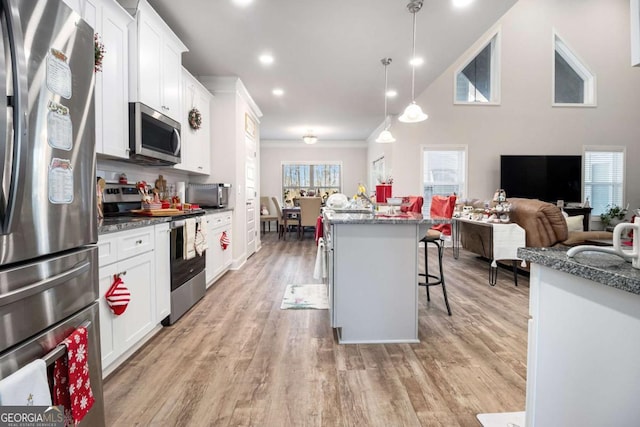 kitchen featuring appliances with stainless steel finishes, a breakfast bar, pendant lighting, a kitchen island, and white cabinets