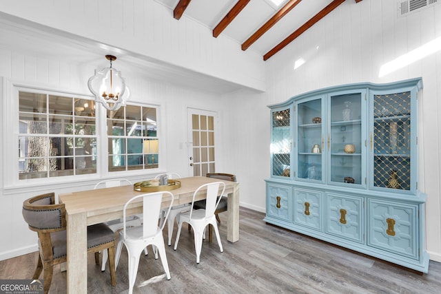 dining area with a chandelier, lofted ceiling with beams, and hardwood / wood-style flooring