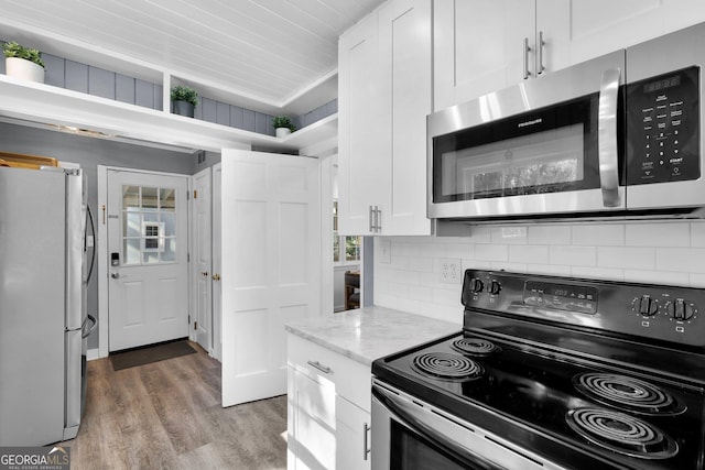 kitchen with appliances with stainless steel finishes, white cabinets, backsplash, and light stone counters