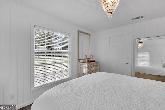 bedroom with an inviting chandelier and wooden walls