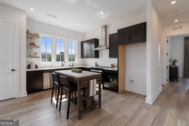 kitchen featuring electric range oven, tasteful backsplash, light hardwood / wood-style floors, and wall chimney exhaust hood