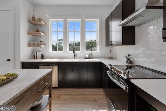 kitchen with wall chimney exhaust hood, light hardwood / wood-style flooring, stainless steel dishwasher, decorative backsplash, and range with electric stovetop