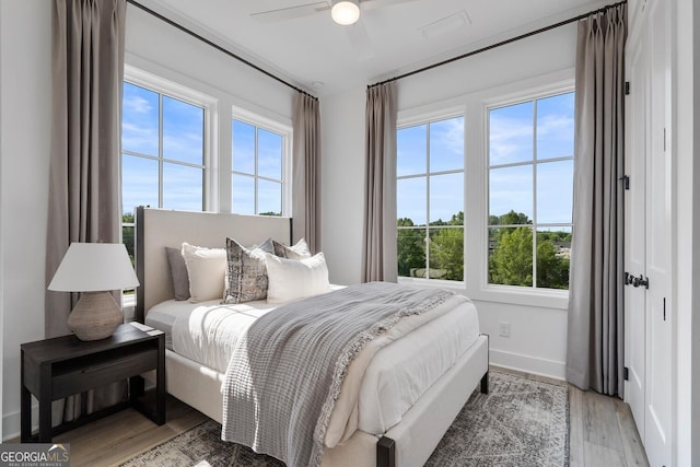 bedroom with hardwood / wood-style floors, ceiling fan, and multiple windows