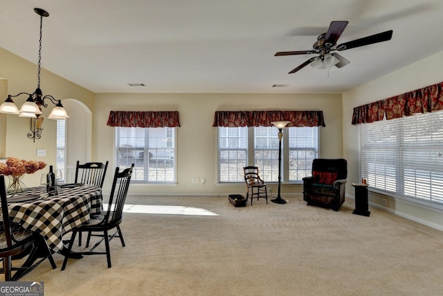 dining space featuring ceiling fan with notable chandelier, a wealth of natural light, and light carpet