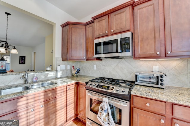 kitchen featuring a chandelier, appliances with stainless steel finishes, light stone countertops, pendant lighting, and sink