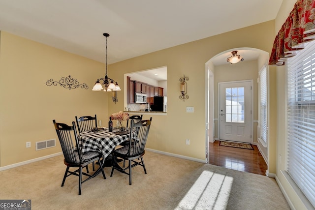 carpeted dining space featuring a notable chandelier