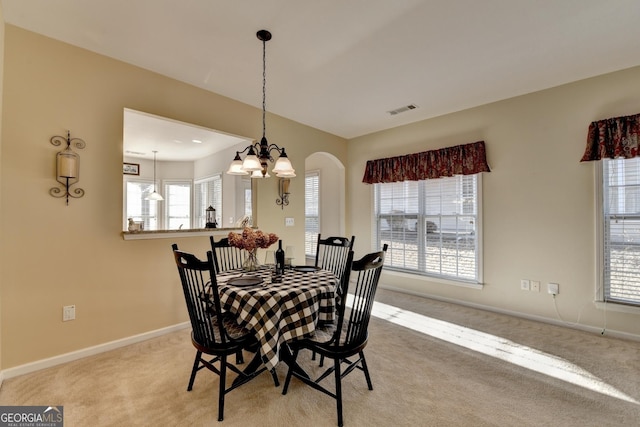 dining space with an inviting chandelier, light carpet, and plenty of natural light