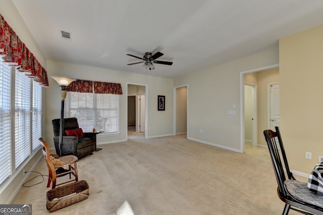 living area featuring light colored carpet and ceiling fan