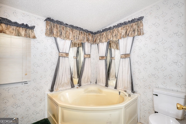 bathroom featuring a textured ceiling, a bath, and toilet