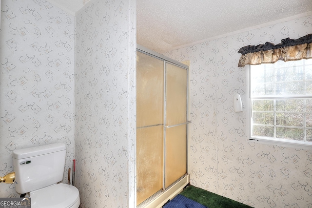 bathroom with a textured ceiling, a shower with shower door, and toilet