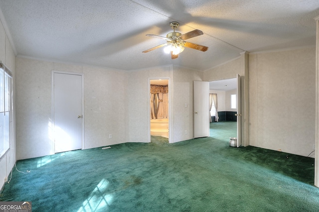 empty room featuring dark carpet, ceiling fan, vaulted ceiling, and crown molding