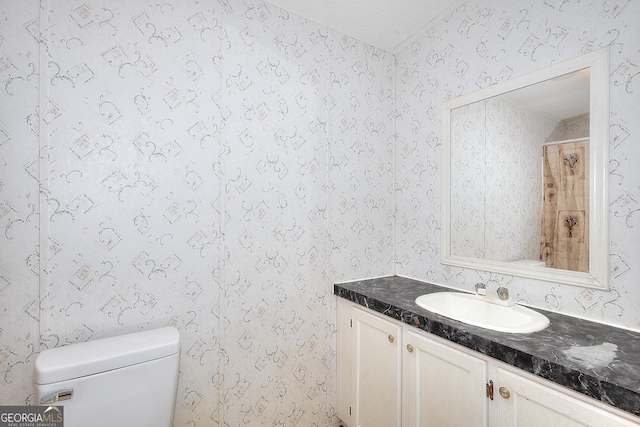 bathroom with toilet, vanity, and walk in shower