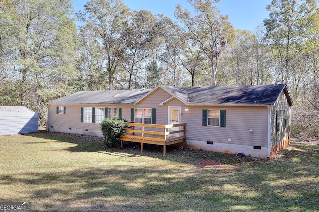 rear view of house featuring a deck, a yard, and a storage unit