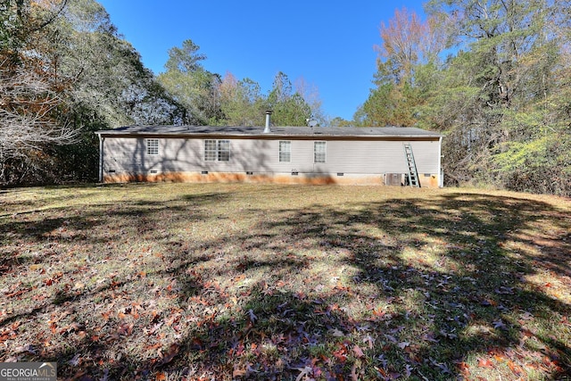 rear view of property with cooling unit and a lawn