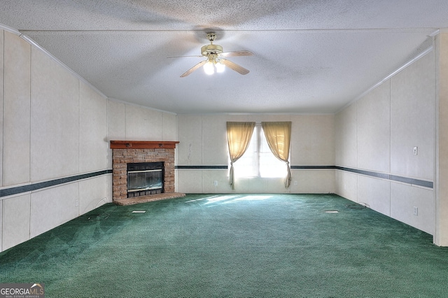 unfurnished living room featuring a textured ceiling, ceiling fan, a fireplace, and dark carpet