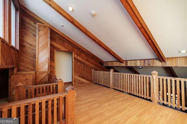 additional living space featuring hardwood / wood-style flooring, wooden walls, and vaulted ceiling with beams