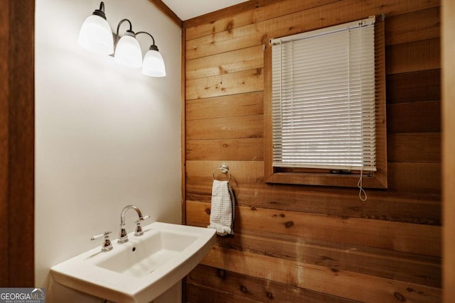 bathroom featuring sink and wood walls