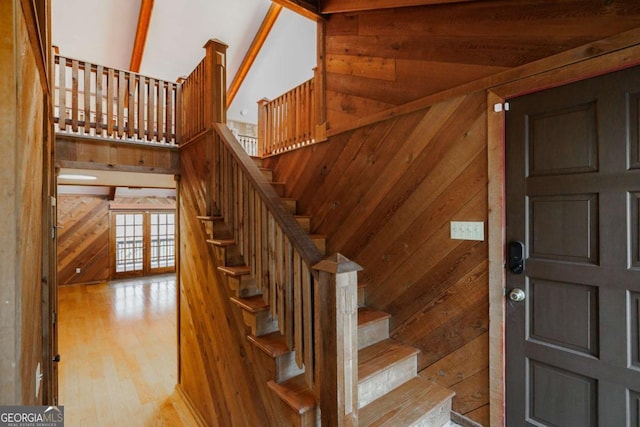 staircase featuring wood walls, hardwood / wood-style floors, and vaulted ceiling