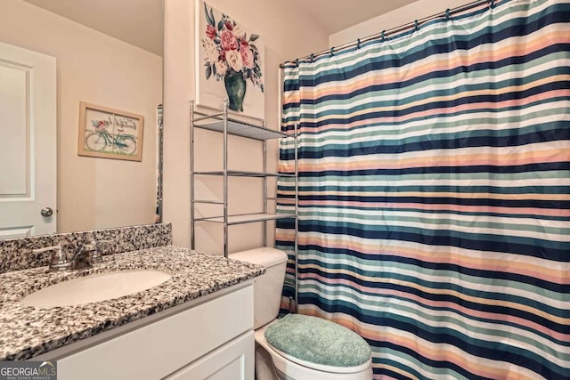 bathroom featuring toilet, vanity, and walk in shower