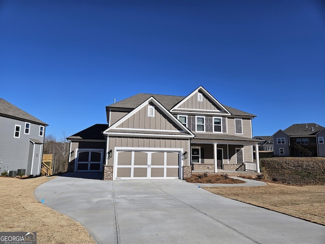 craftsman-style house featuring a porch, a garage, brick siding, concrete driveway, and board and batten siding