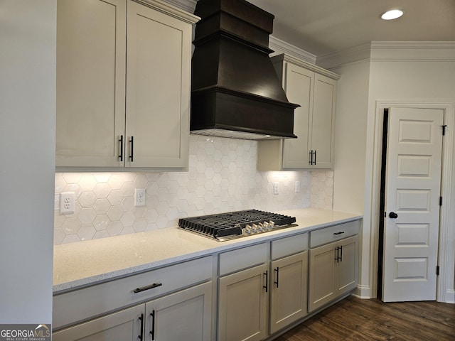 kitchen with premium range hood, backsplash, dark wood finished floors, crown molding, and stainless steel gas cooktop