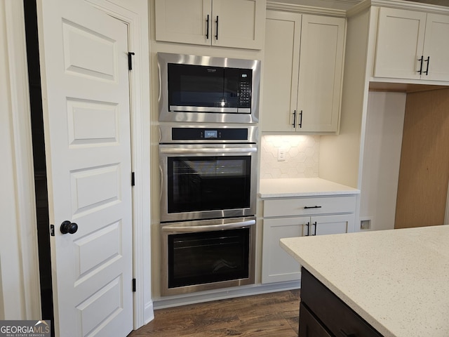 kitchen featuring dark wood-style floors, decorative backsplash, appliances with stainless steel finishes, and light stone countertops