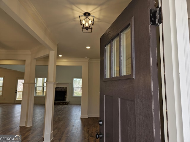 foyer featuring dark wood-style floors, a brick fireplace, and ornamental molding