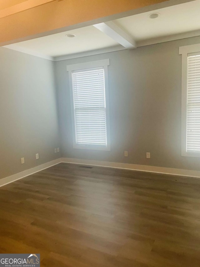 unfurnished room with beam ceiling, a healthy amount of sunlight, and dark hardwood / wood-style floors