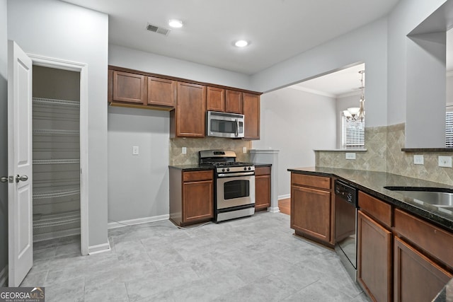 kitchen with decorative light fixtures, a chandelier, appliances with stainless steel finishes, dark stone counters, and decorative backsplash