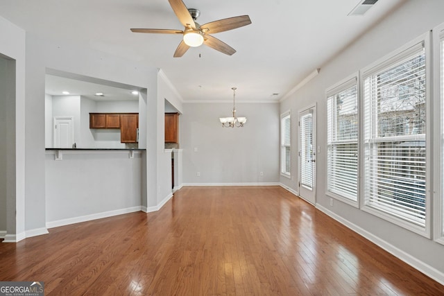 unfurnished living room featuring crown molding, ceiling fan with notable chandelier, and hardwood / wood-style floors