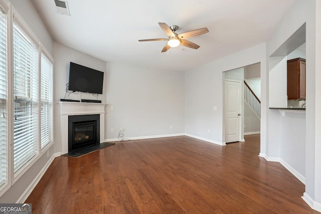 unfurnished living room featuring dark wood-type flooring and ceiling fan