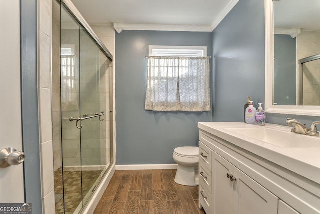 bathroom with toilet, a shower with door, vanity, and crown molding