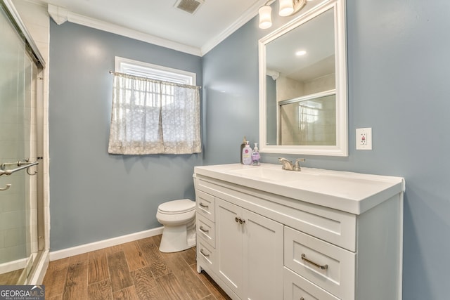 bathroom featuring toilet, ornamental molding, walk in shower, and vanity