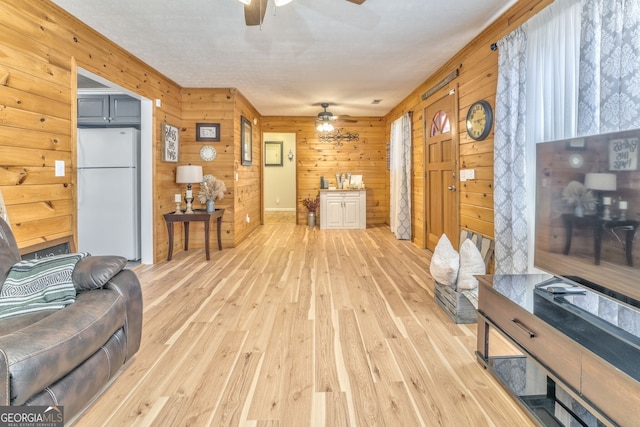 living room featuring light hardwood / wood-style floors, ceiling fan, and wooden walls