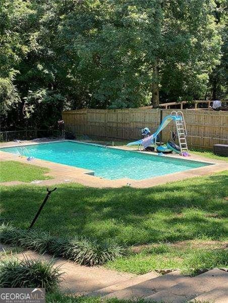 view of swimming pool featuring a yard and a water slide