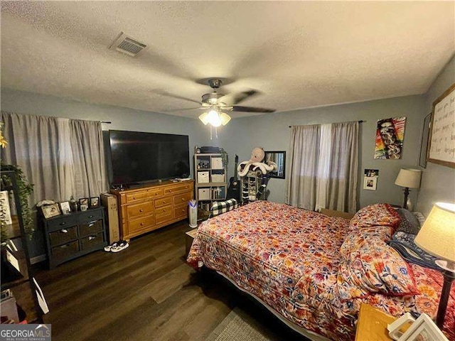 bedroom with a textured ceiling, ceiling fan, and dark hardwood / wood-style floors