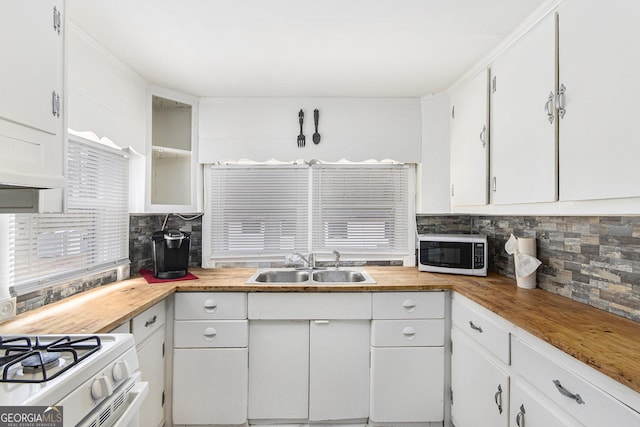 kitchen featuring sink, white gas stove, white cabinets, and decorative backsplash