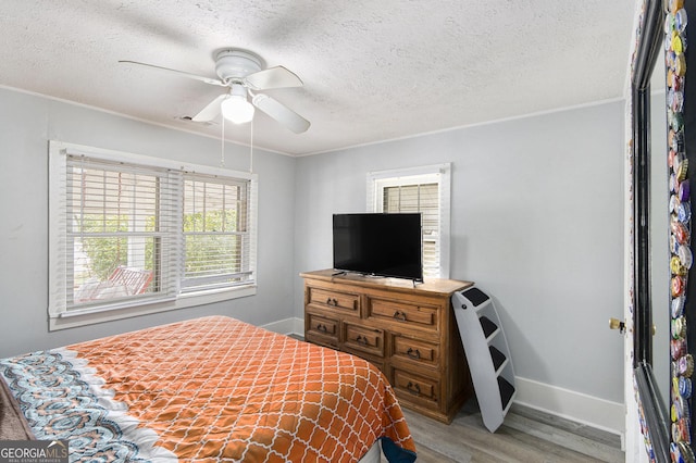 bedroom with a textured ceiling, ornamental molding, light hardwood / wood-style floors, and ceiling fan