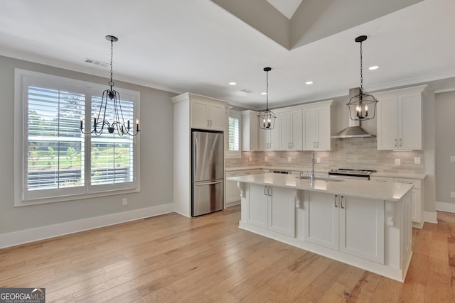 kitchen featuring white cabinets, stainless steel appliances, an island with sink, pendant lighting, and sink