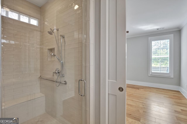 bathroom featuring an enclosed shower, hardwood / wood-style flooring, and crown molding